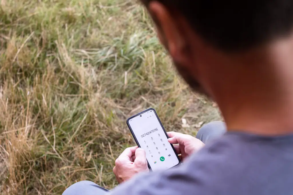Obdachloser Mann hat Erstberatungs-Telefonnummer vom Verein Wohnen am Smartphone gewählt.